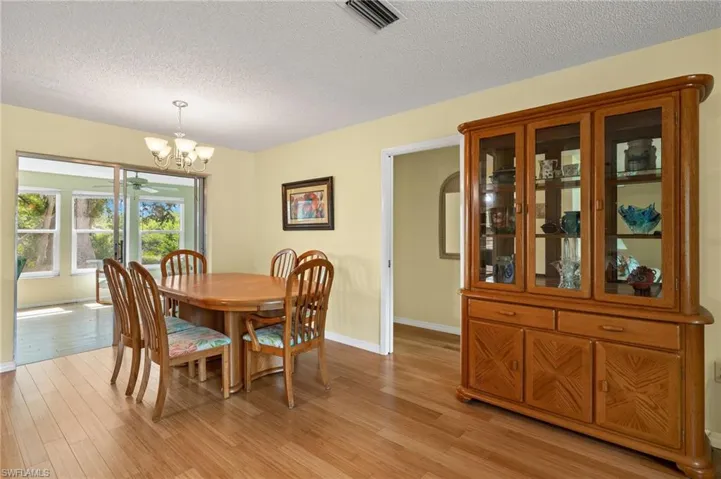 Dining room featuring light wood-type flooring, a textured ceiling, and an inviting chandelier