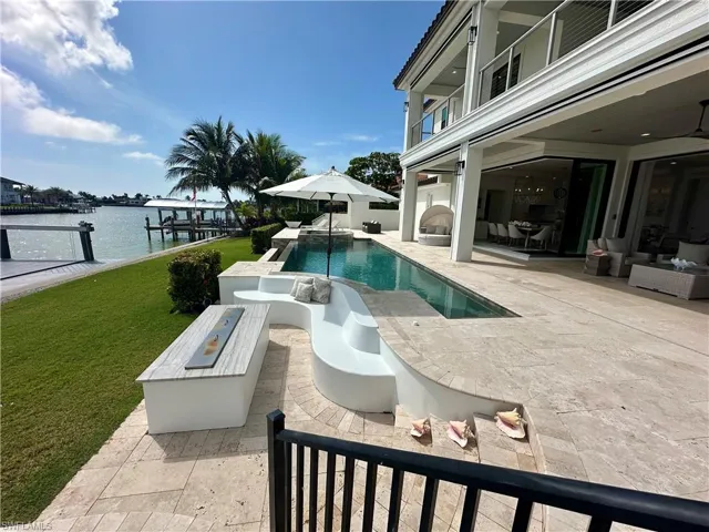 View of pool featuring a patio area, a water view, a yard, and a fireplace