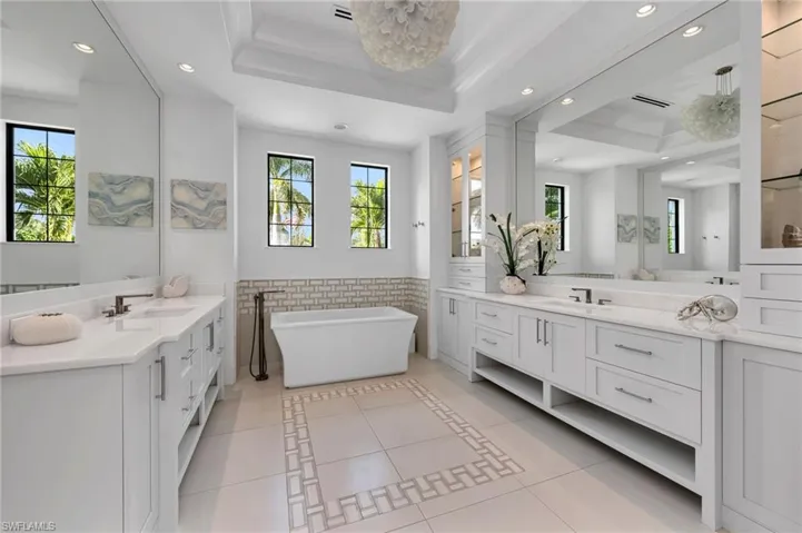 Bathroom with a raised ceiling, tile walls, tile patterned floors, a tub, and vanity