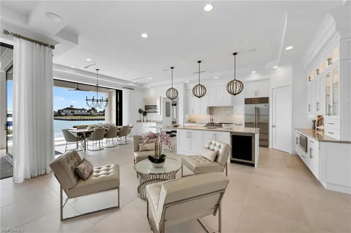 Tiled living room featuring sink, a notable chandelier, a water view, and wine cooler