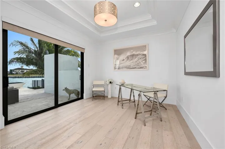 Dining room featuring a water view, crown molding, light hardwood / wood-style floors, and a raised ceiling