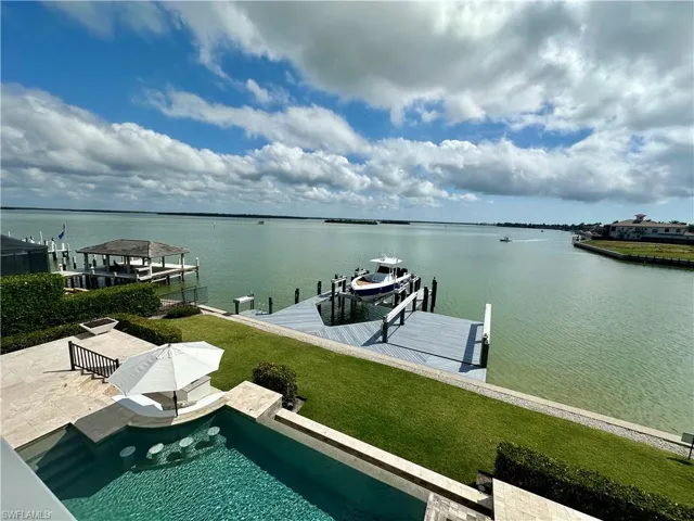 View of dock with a lawn and a water view