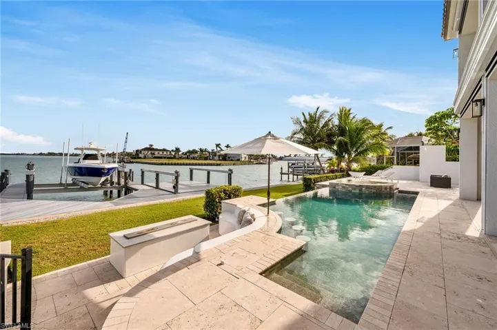 View of swimming pool featuring a patio, a water view, an in ground hot tub, and a boat dock