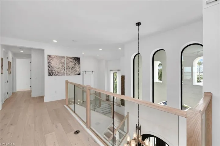 Hallway featuring light hardwood / wood-style flooring and a notable chandelier