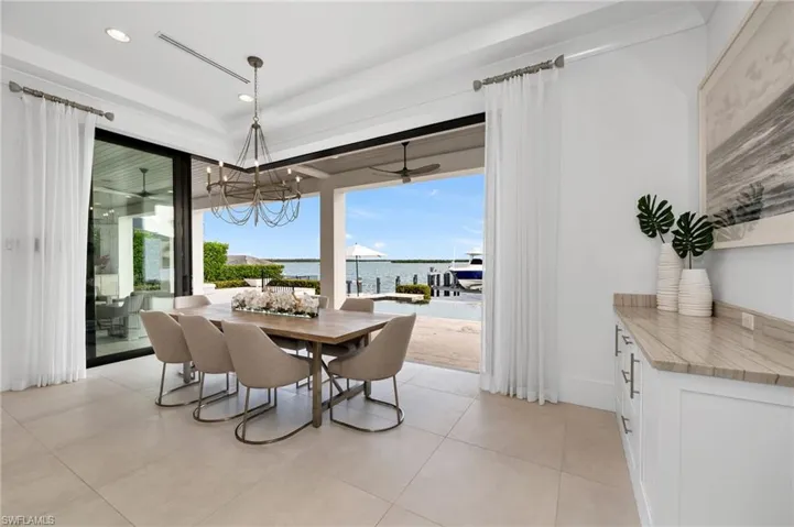Tiled dining area featuring ceiling fan with notable chandelier and a water view