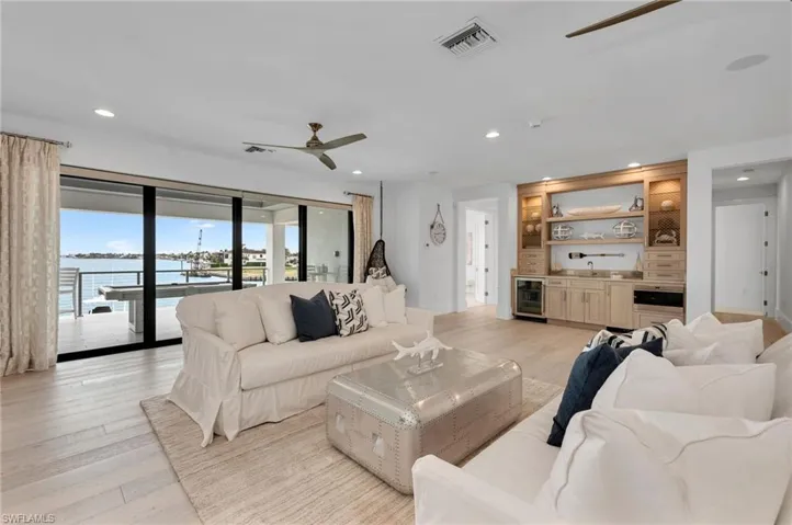 Living room with ceiling fan, sink, light wood-type flooring, a water view, and beverage cooler