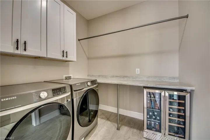 Laundry Room has been completed for you with cabinets, Beverage Cooler, Folding Table and Hanging Clothes Pole