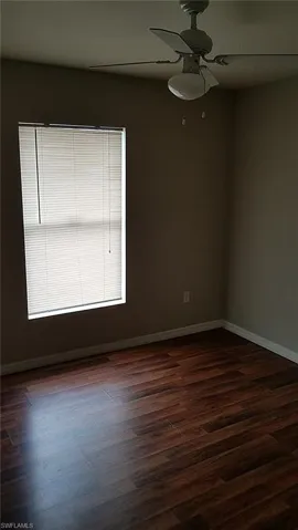 Unfurnished room featuring dark wood-style flooring and a ceiling fan