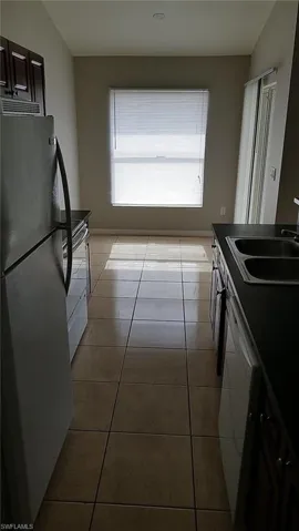 Kitchen featuring dark countertops, white appliances, and light tile patterned floors