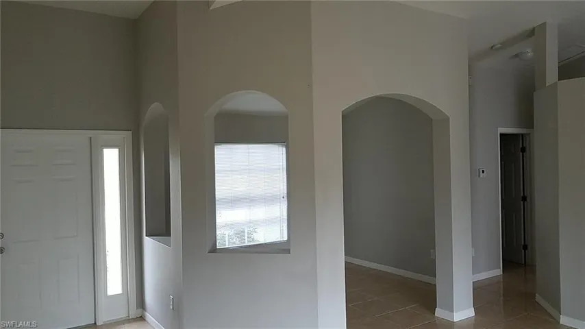 Entrance foyer featuring a towering ceiling, light tile patterned floors, and arched walkways