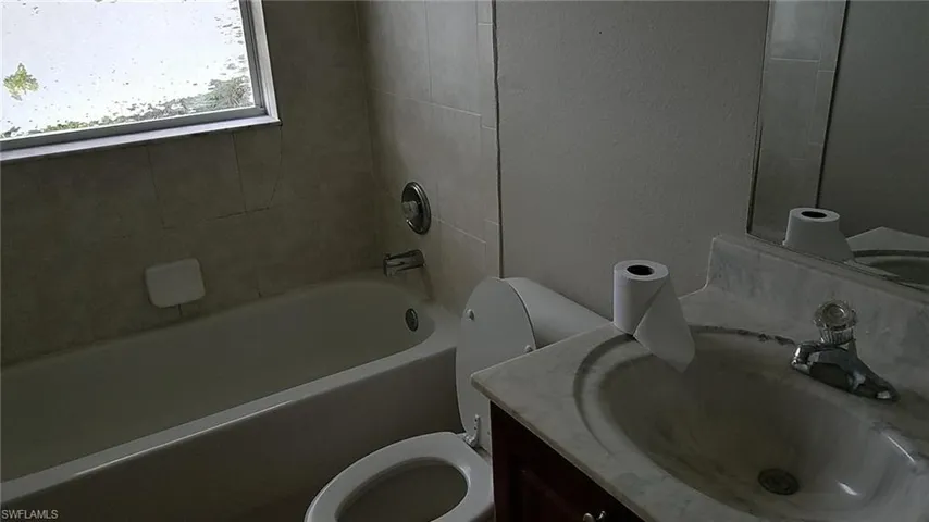 Full bathroom featuring vanity, shower / bath combination, and a textured wall