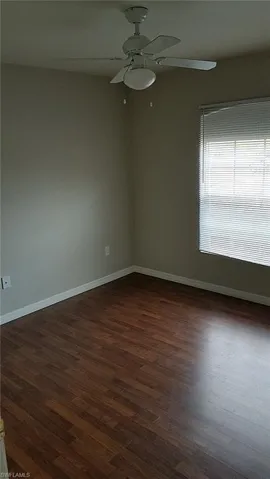 Unfurnished room with dark wood finished floors and a ceiling fan