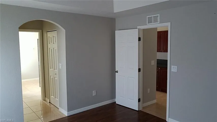 Unfurnished bedroom with arched walkways, light wood-style flooring, and a closet