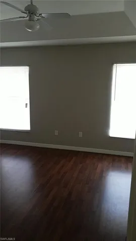 Unfurnished room featuring dark wood finished floors and ceiling fan