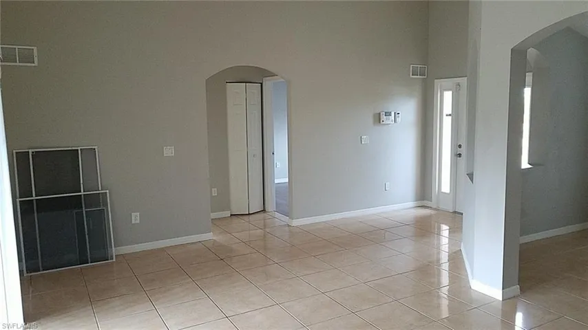 Spare room featuring arched walkways, light tile patterned floors, and a high ceiling
