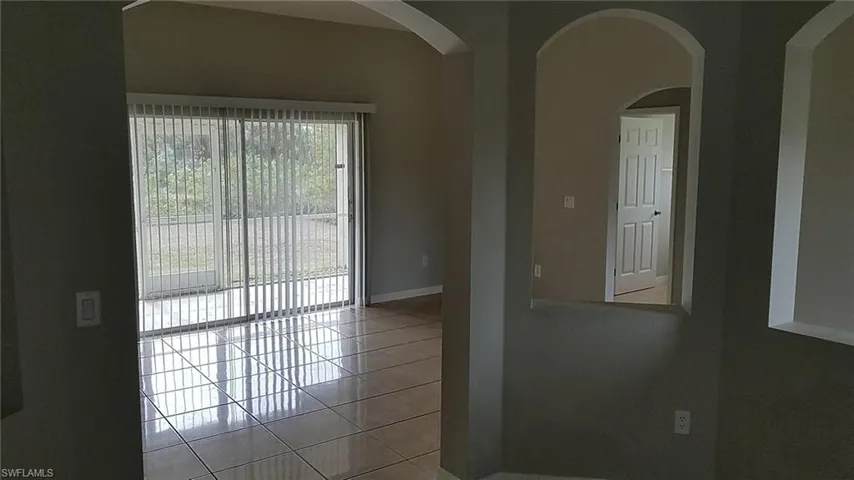 Tiled spare room featuring arched walkways