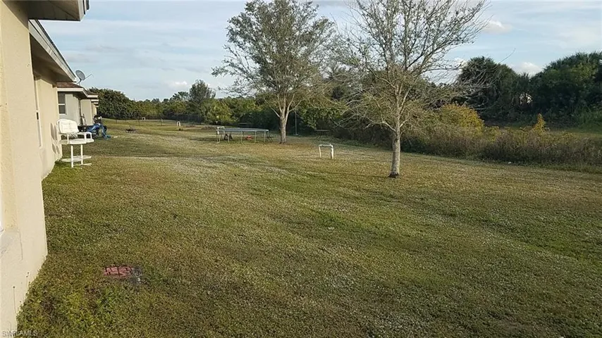 View of grassy yard with view of wooded area