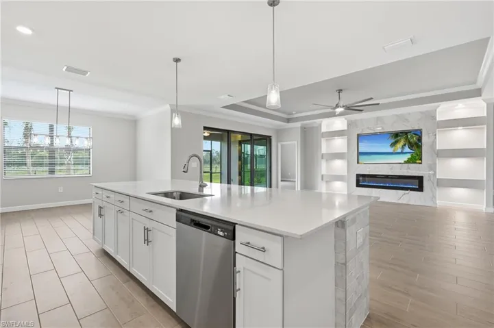 Kitchen island featuring a single-basin sink with a gooseneck faucet, integrated dishwasher, and pendant lighting