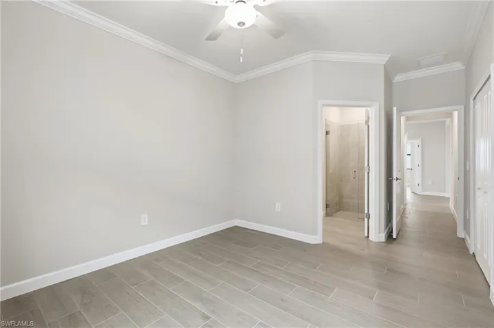 Interior space featuring light gray walls, wood-finish tile flooring, crown molding, and a ceiling fan