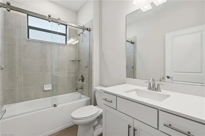 Bathroom featuring a white vanity with an integrated sink, brushed nickel fixtures, and a large mirror