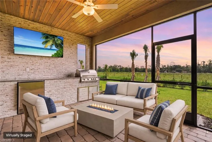 Screened patio featuring a wood-finish ceiling, paver flooring, stone accent wall, and built-in outdoor kitchen with grill and refrigerator