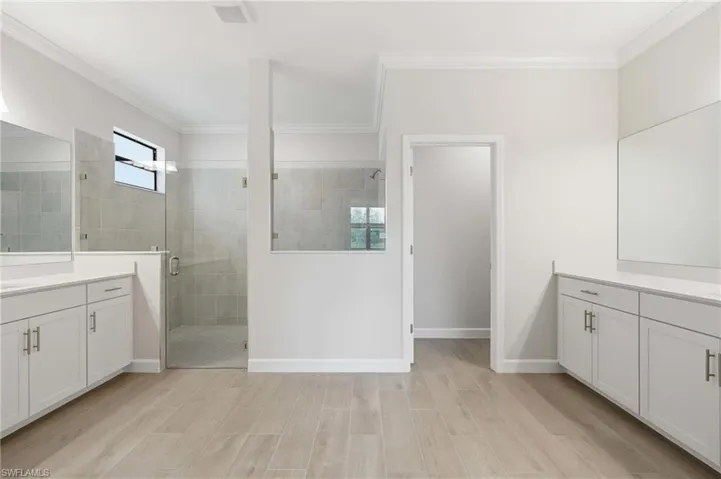 Dual vanity bathroom featuring wood-finish tile flooring and a glass-enclosed shower with tiled walls