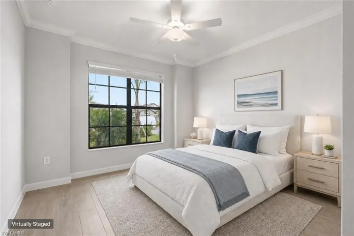 Bedroom featuring a large multi-pane window, wood-finish flooring, crown molding, and a ceiling fan with integrated lighting