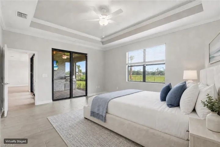 Expansive room featuring a tray ceiling, ceiling fan, and light wood-finish flooring