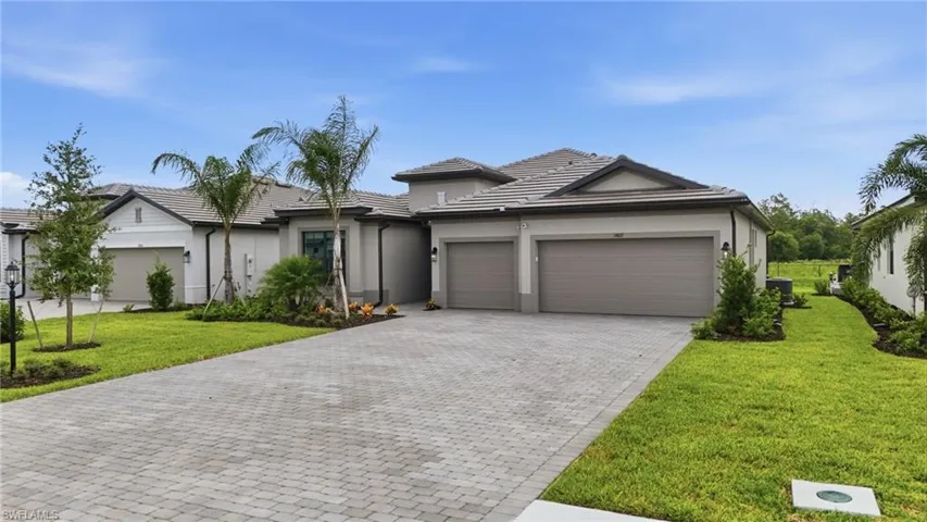 Contemporary single-story residence featuring a paver driveway, two-car garage, and a tiled roof