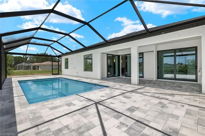 View of pool with glass enclosure and a patio