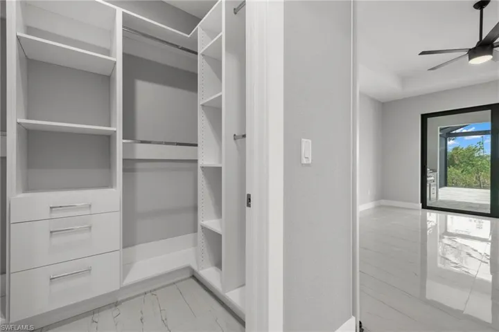Spacious closet with ceiling fan and light tile patterned flooring