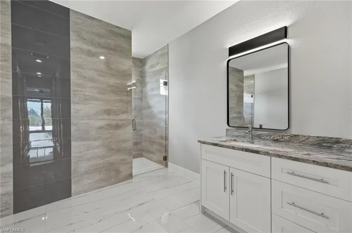 Bathroom featuring vanity, tile patterned flooring, and a shower with shower door