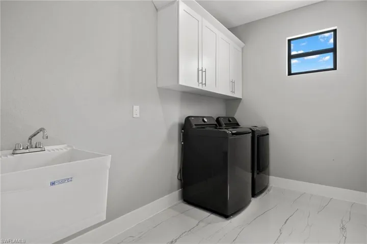 Laundry room featuring sink, light tile patterned floors, cabinets, and separate washer and dryer
