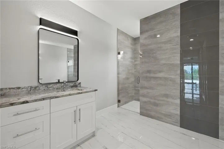 Bathroom with an enclosed shower, tile patterned floors, and vanity