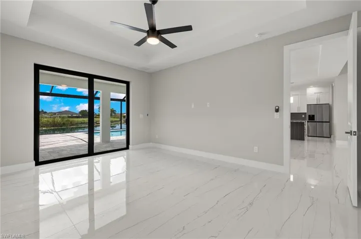 Tiled empty room with ceiling fan and a raised ceiling