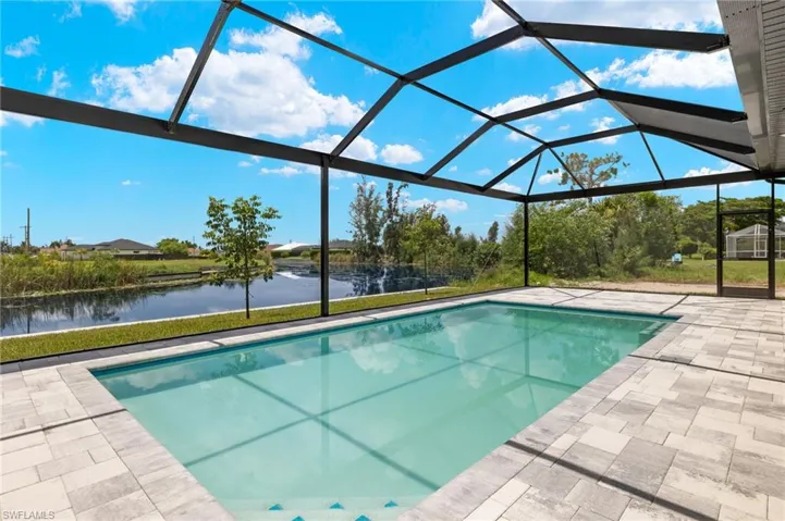 View of swimming pool with glass enclosure, a water view, and a patio area