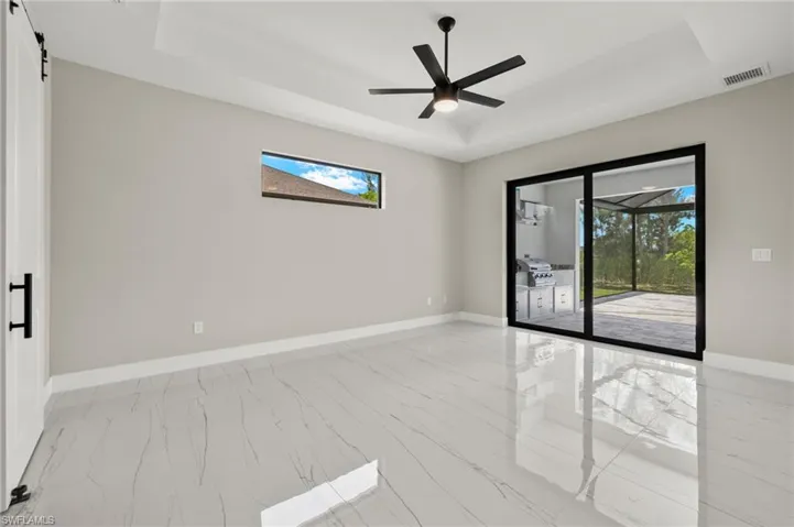 Tiled empty room featuring ceiling fan and a raised ceiling