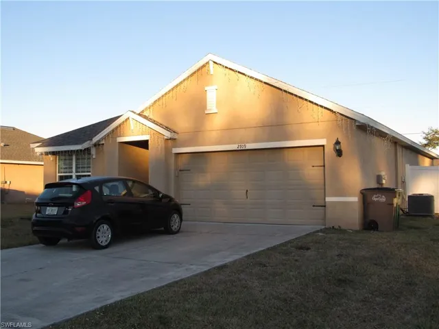 View of front of house with driveway, stucco siding, a garage, and a front lawn