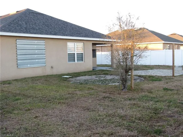 Back of property with stucco siding and roof with shingles