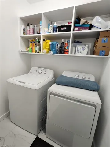 Laundry area with washer and clothes dryer and light marble finish floors