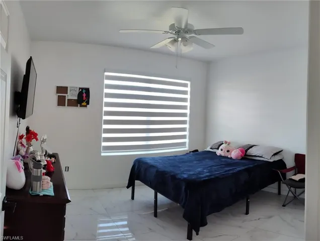 Bedroom with ceiling fan and light marble finish flooring