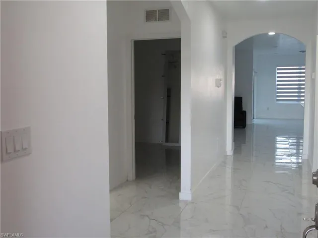 Hallway featuring arched walkways and light marble finish floors