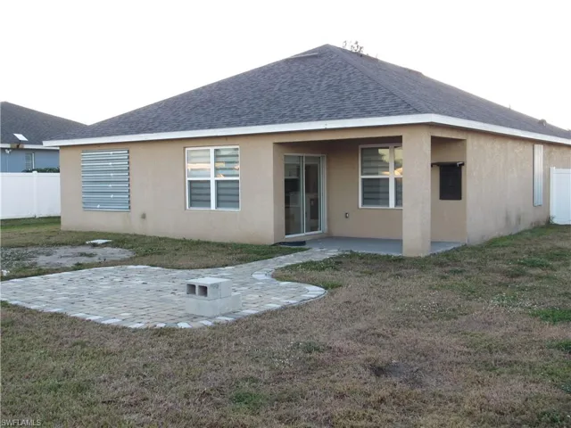 Back of property with a patio, a shingled roof, and stucco siding