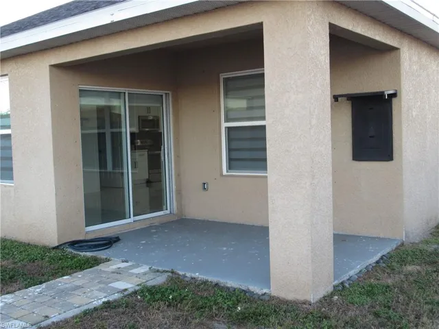 Property entrance with stucco siding, a patio, and electric panel