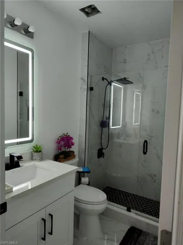 Full bathroom featuring a marble finish shower and vanity