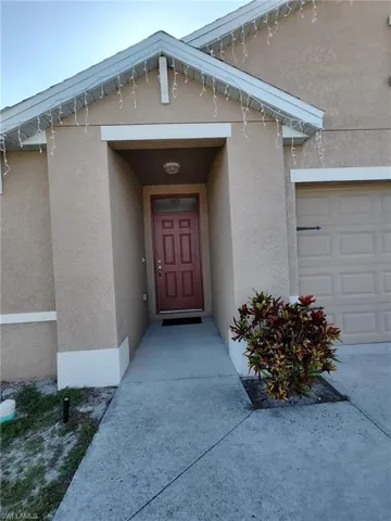 View of exterior entry with a garage and stucco siding