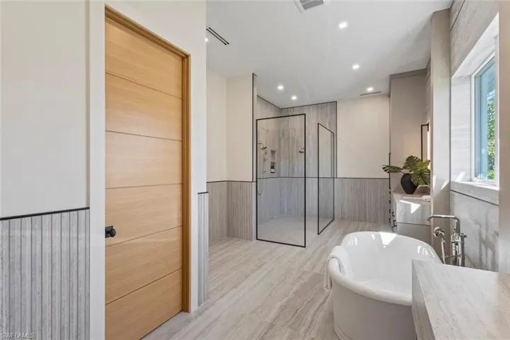 Full bath featuring wainscoting, a shower stall, recessed lighting, a freestanding bath, and vanity