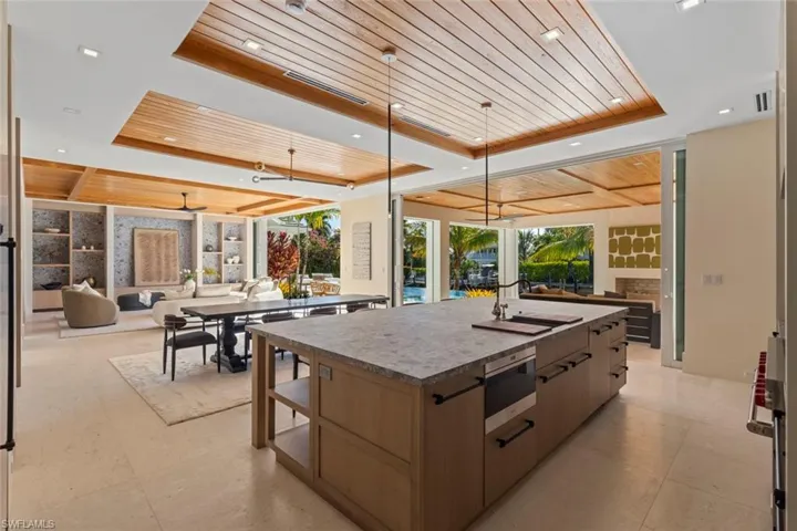 Kitchen featuring wooden ceiling, a raised ceiling, open floor plan, a kitchen island with sink, and modern cabinets