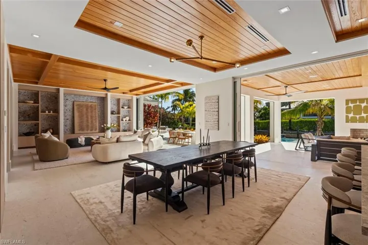 Dining area featuring wood ceiling, a tray ceiling, a sunroom, a ceiling fan, and floor to ceiling windows