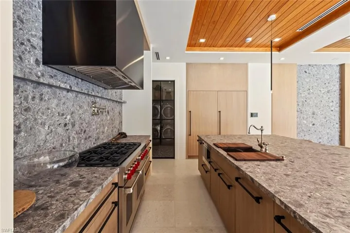 Kitchen with a raised ceiling, wooden ceiling, dark stone countertops, extractor fan, and range with two ovens